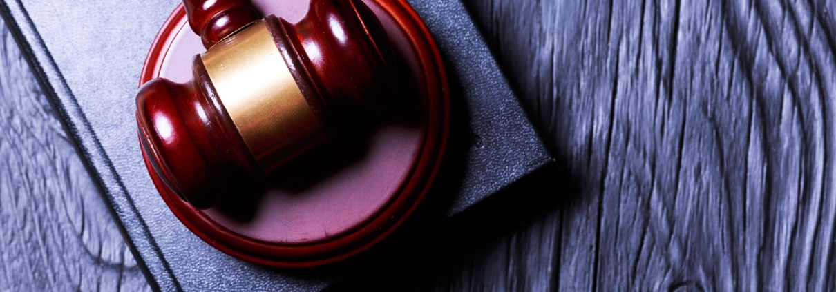 Gavel resting on a book on a dark wooden surface