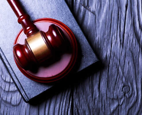 Gavel resting on a book on a dark wooden surface