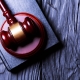 Gavel resting on a book on a dark wooden surface